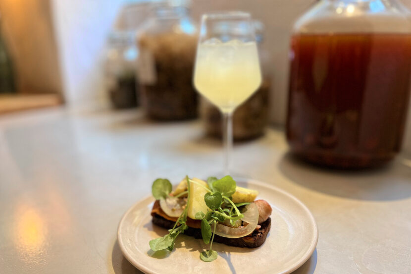 Typisches dänisches Smørrebrød auf Roggenbrot mit frischen Zutaten, serviert mit einem Getränk im Hintergrund