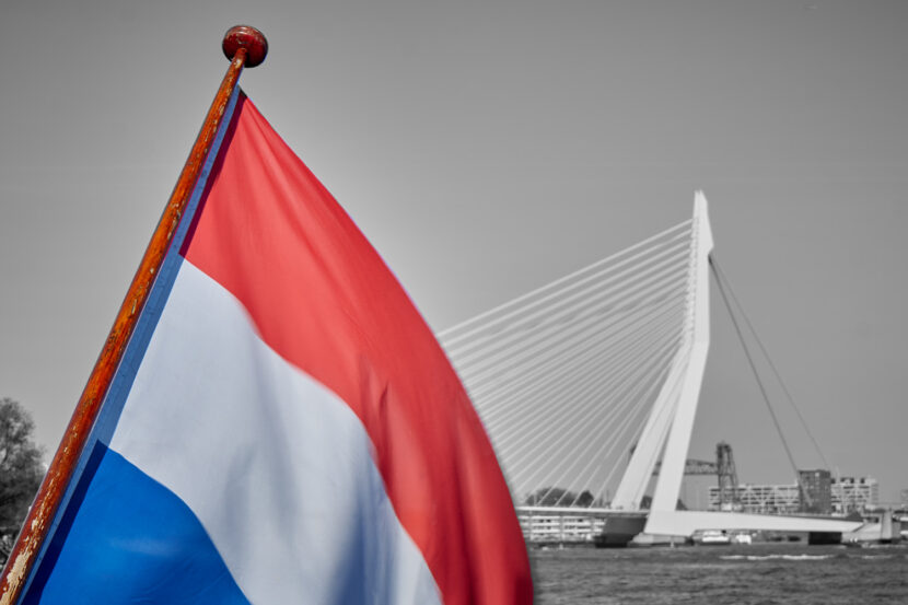 Niederländische Flagge im Vordergrund vor der Erasmusbrücke in Rotterdam, aufgenommen auf der Maas