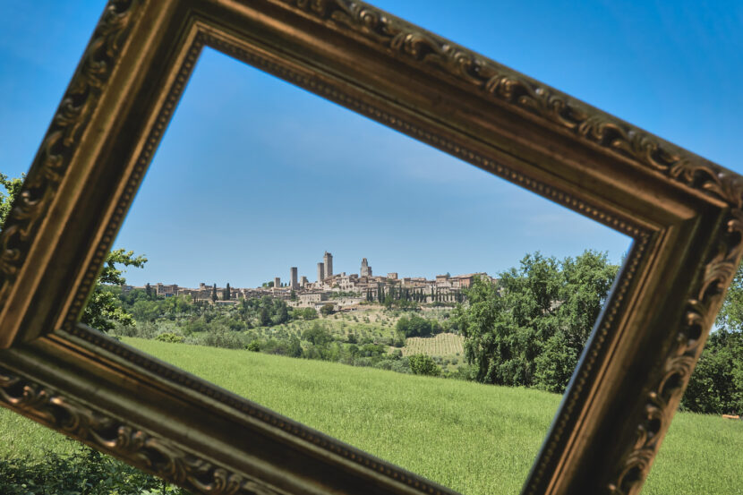 Blick auf die Türme von San Gimignano durch einen Bilderrahmen, eingebettet in die toskanische Landschaf