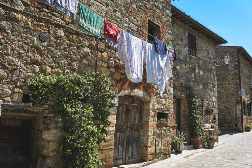 Rustikale Natursteinhäuser mit Wäscheleine in einer engen Gasse des mittelalterlichen Orts Monteriggioni