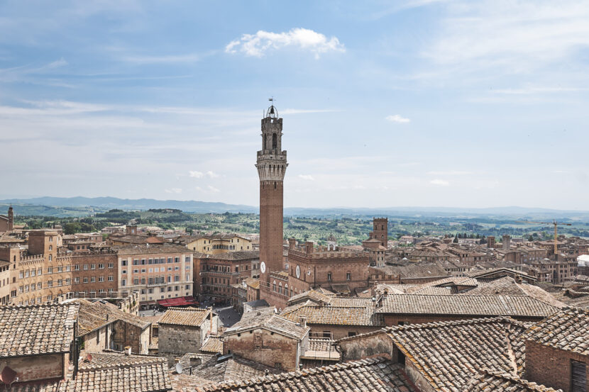 Panoramablick über die Dächer von Siena mit dem Torre del Mangia und der toskanischen Hügellandschaft im Hintergrund