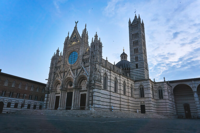 Der Dom von Siena mit seiner kunstvollen Marmorfassade und dem markanten Glockenturm auf der Piazza del Duomo am sehr frühen Morgen aufgenommen.