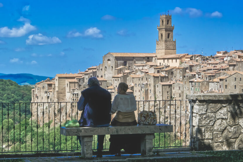 Zwei Menschen mit Blick auf die historische Tuffsteinstadt Pitigliano, die spektakulär auf einem Felsrücken thront