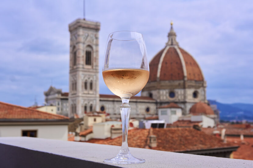 Weinglas auf einer Dachterrasse mit Blick auf die Kathedrale Santa Maria del Fiore in Florenz bei Abendstimmung